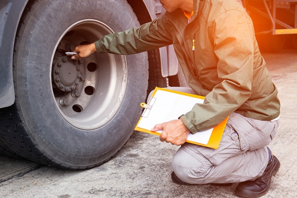 A person with a clipboard inspecting a large truck tire. (280910096)